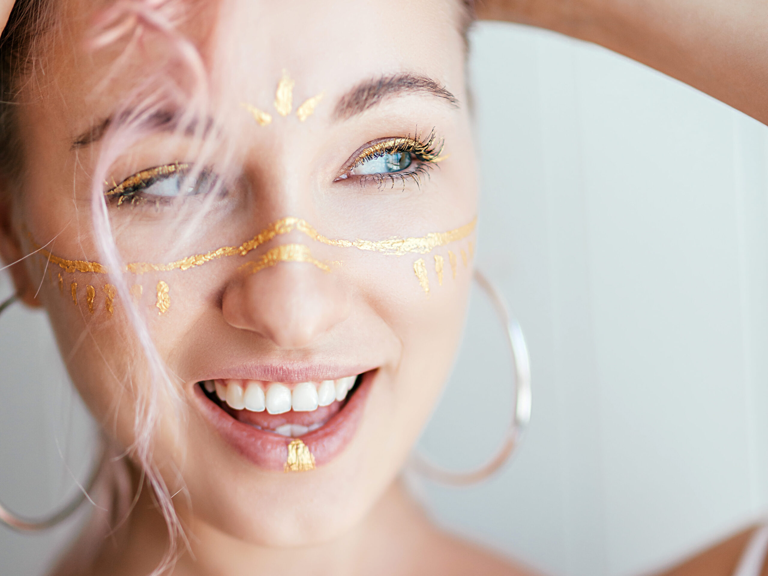 Junge fröhliche Frau mit goldenen Akzenten im Gesicht. 