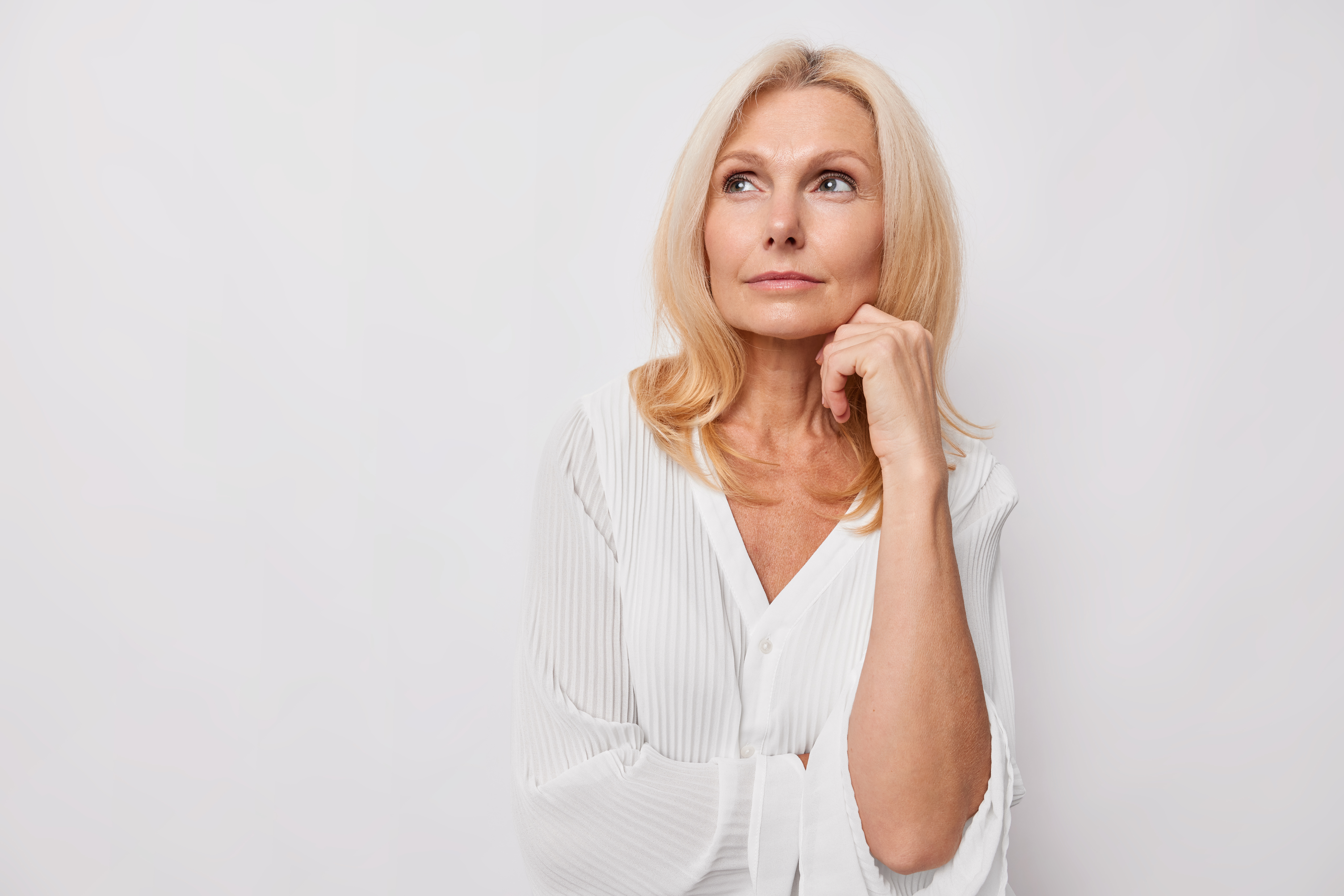 Blonde Frau mittleren Altern schaut nachdenklich nach links
