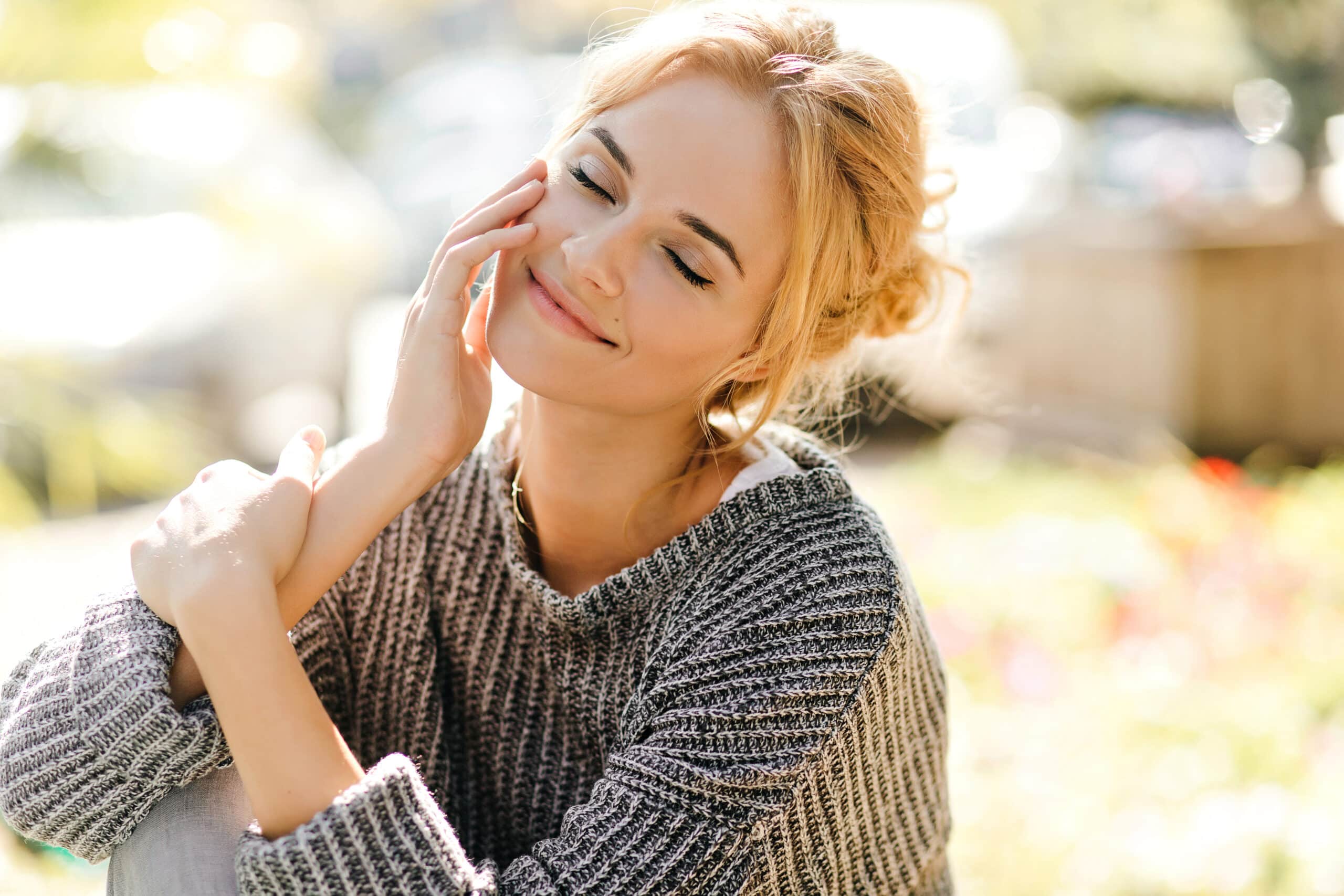 junge frau mit geschlossenen augen sitzt freundlich im Gras